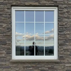 Cleaned grid window on a stone-faced home with the evening sky in the glass